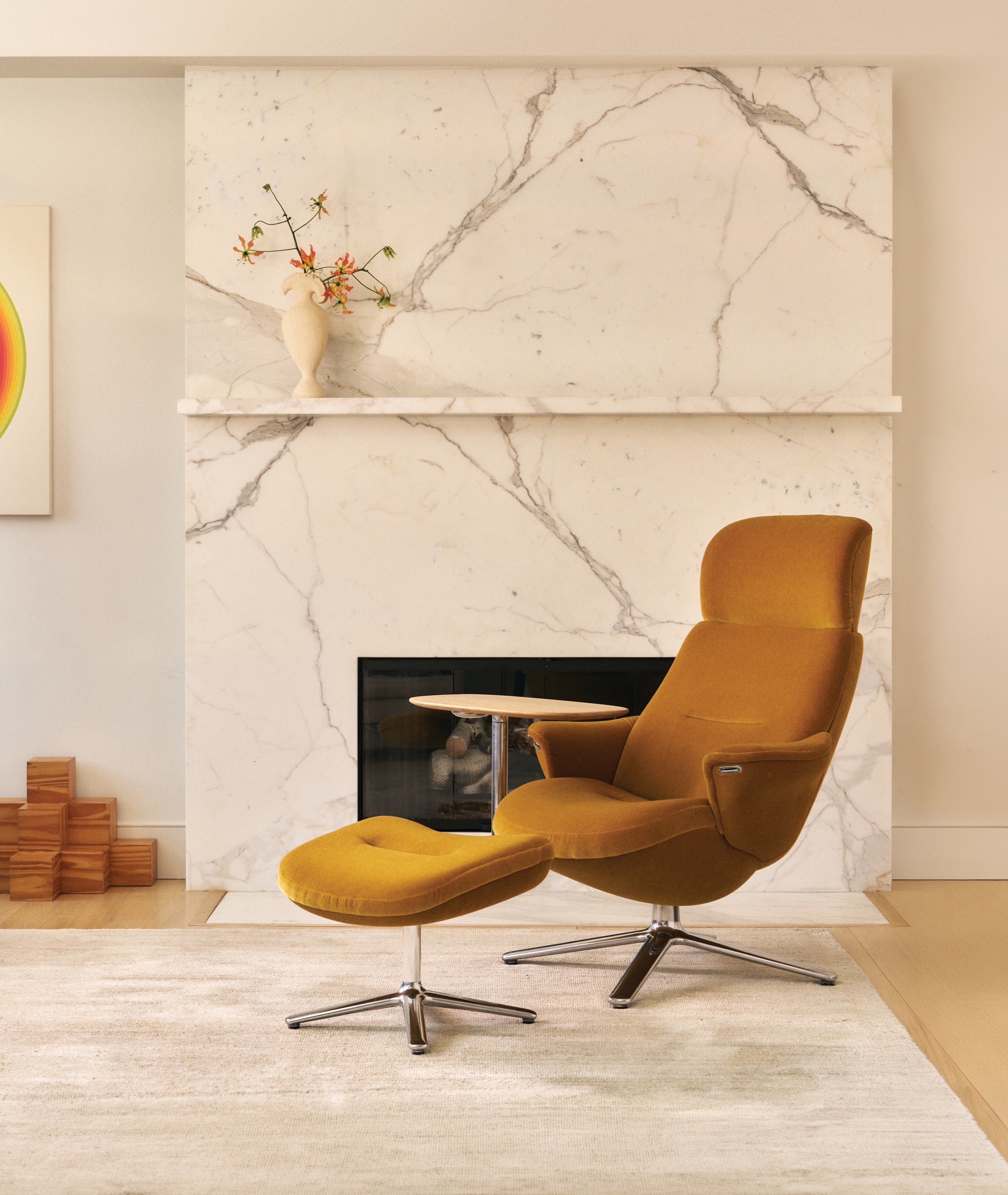 Mustard Humanscale Diffrient Lounge chair with ottoman and lside table in front of fireplace